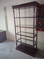 Full view of the tall brown wooden shelf showing the wooden and glass shelving.
