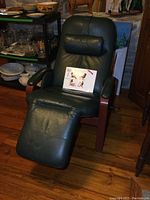 Front view of reclining chair with green leather upholstery and wood frame