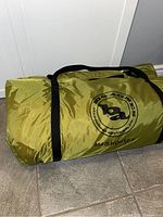 Olive green rolled carry bag lying on tile floor, side view