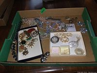 Full cardboard tray showing assorted brooches, necklaces, pins