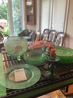 Wide view of green glass items including dessert plates, bowls, and candle holders on table