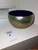 Side view showing iridescent exterior with fine gilded line design on cobalt glass bowl