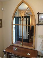 Front view of the large wooden framed mirror with church window style arched top and visible crossbars.