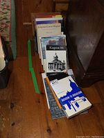 Wide view of upright and stacked books on wooden floor, showing Buckskin to Broadloom and Kingston 300 front titles