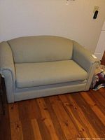 Front view of loveseat upholstered in pale green patterned fabric showing rounded armrests and cushion.