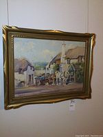 Framed oil painting of rural village street with horses and carts.