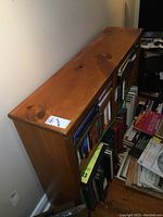 Full view of solid pine bookshelf against a wall with visible wood grain and knots, filled with books and other items (not included in sale).