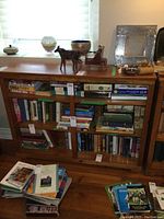 Front view of pine bookshelf filled with books and decorative items on top.