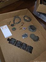 Overview of assorted metal mesh purse, pill boxes, bracelets and pins on cardboard tray