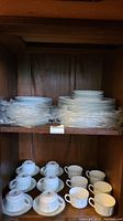 Photo showing stacks of plates (dinner, salad, dessert) and teacups on shelves