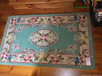 Full view of vintage floral rug showing turquoise background and multicolor floral designs.