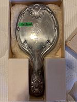Sterling silver handheld mirror in original box with ornate design and engraved monogram