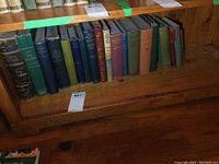 Full shelf view showing numerous vintage hardcover books with green, blue, brown colored bindings.