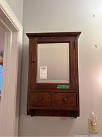 Front view of wooden medicine cabinet showing closed door and drawers