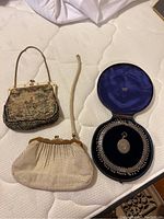 Overall view of two purses, jewelry case, necklace and locket