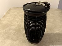 Front and side views of the black Stinger brand outdoor mosquito and insect killer. Shows the protective grid, top hanging loop, and power cord.