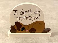 Front view of the decorative shelf sitter showing the text and sleepy dog design clearly.