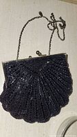 Black beaded clutch with metallic chain handle in shell-shaped design