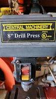 Close-up of the Central Machinery logo, model 8" Drill Press label, and on/off switch.