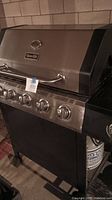Front view of Dyna-Glo gas grill showing four control knobs and hinged lid with logo.
