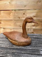 Side profile of the wooden carved goose decoy showing the neck, head, and body with engraved feather details.