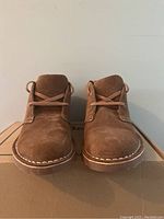Front view of brown suede LL Bean Stonington chukka boots on cardboard box.