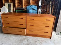 Front view of the teak dresser showing six drawers with inset handles, one drawer partially open revealing swelling damage.