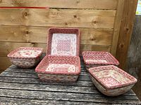Set of five square ceramic baking dishes with red and cream floral and geometric pattern on a wooden surface