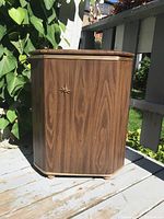 Closed mid-century style laundry hamper with faux wood finish and starburst detail on front.