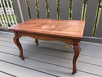 Full view of the rectangular coffee table with visible circular surface mark and curved legs, showing the wood grain and finish.