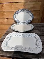 Three blue and white porcelain platters arranged on a wooden table showing their shapes and designs.