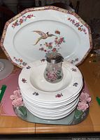 Full view of Czechoslovakian china serving platter with bird and flower design. Bowls stacked in front with floral patterns. A shaker is placed center on bowls.