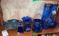 Full lot including cobalt blue glassware items and carnival glass bowl against a wall.