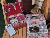 General view of wooden jewelry box with red velvet interior and floral fabric-covered jewelry box with assorted costume jewelry inside
