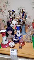 Front view of painted decanter, assorted perfume bottles and pin holders on table