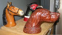 Three figural metal bottle openers shaped as horse, dog, and pheasant heads displayed side by side.