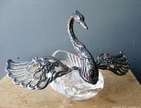 Front angle view showing the swan salt cellar with detailed silver neck and reticulated wings resting on glass base.
