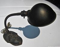 Side view of the vintage adjustable industrial spotlight desk lamp showing ornate metal base and flexible gooseneck arm with large metal shade.