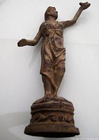 Front view of the cast iron Victorian lady door stop showing detailed draped dress and raised arm holding small object.