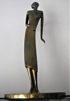 Front view of brass Art Deco flapper lady figurine on round base, showing full figure with one arm on hip.