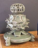 Side view of intact celadon porcelain incense burner showing petal details and rabbit feet