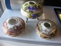 Three Nippon Noritake porcelain vanity boxes on a white surface with natural light.