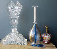 Set of three decorative Bohemian art glass perfume bottles against a gray background
