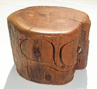 Overall view of the carved wooden box that resembles a tree trunk bole, showing natural wood texture, age cracks, and round wooden knobs on drawers.