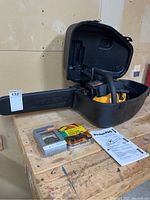 Full kit shown in open hard plastic carrying case on workbench, displaying chainsaw body, chains, manual.