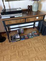 Photo showing the Insignia Blu-ray player and JVC DVD/VHS player stacked on a table with collection of DVD and VHS movies underneath.