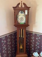 Full front view of Emperor Westminster chime grandfather clock showing bonnet, columns, weights and pendulum