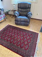 Brown leather La-Z-Boy swivel recliner and red wool rug on parquet floor