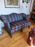 Front and side view of the striped fabric loveseat showing upholstery pattern, arm covers, and hardwood legs.