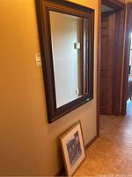 Mirror mounted on wall showing dark wood frame and beveled clear glass